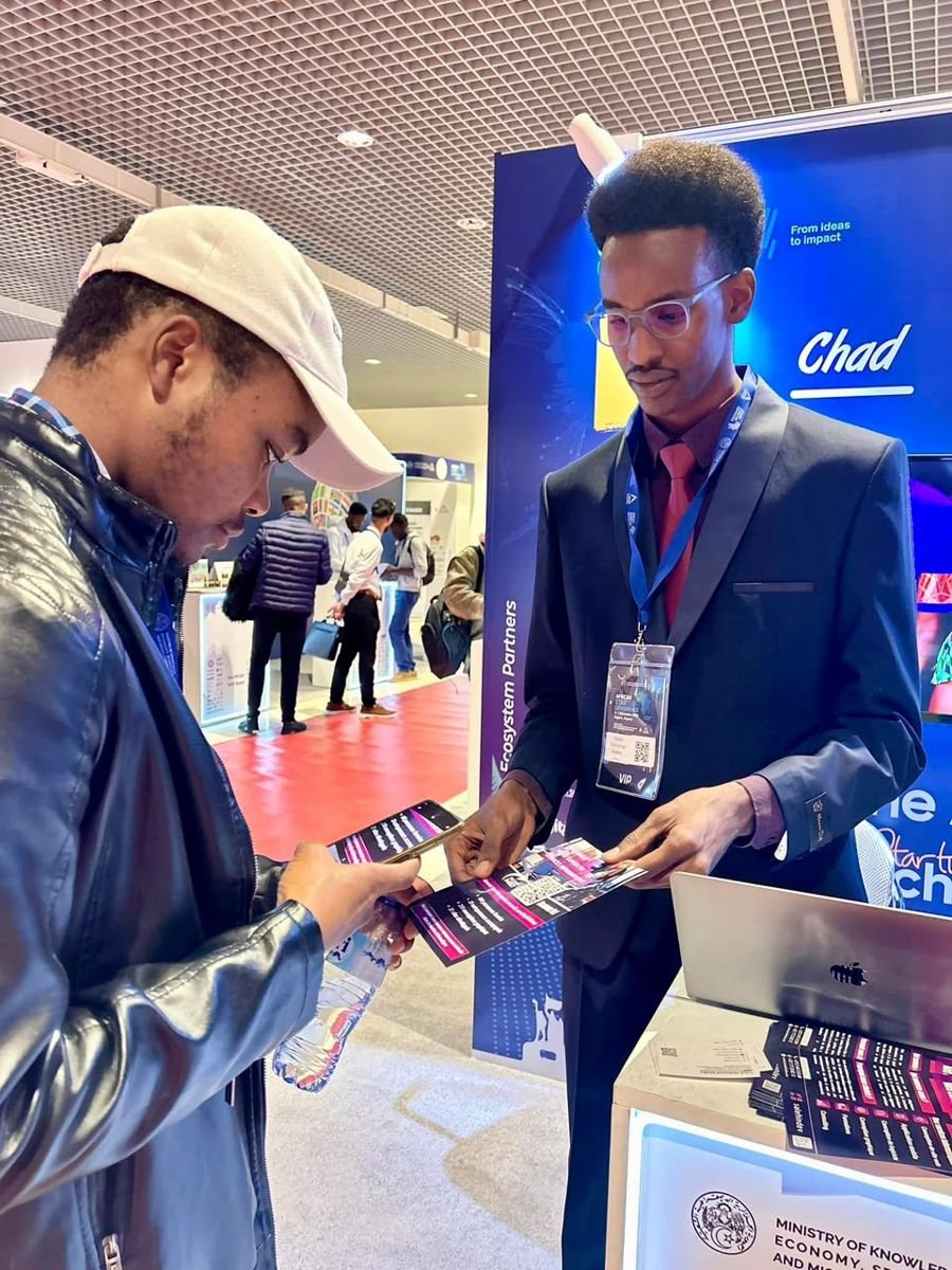 Présentation de flyers à un visiteur au stand du Tchad