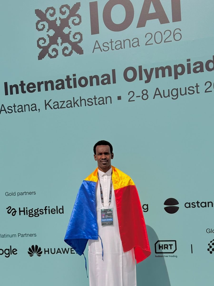 Saleh Mahamat Issaka, drapeau du Tchad sur les épaules, devant le panneau de l'IOAI 2026 à Astana